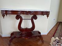 Full frontal view of wooden side table with harp design base and marble top