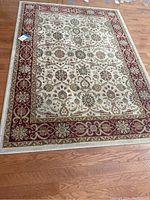 Full view of the Persian crown rug showing floral medallion and bordered design, placed on a hardwood floor.