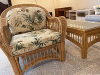 Rattan armchair and matching coffee table on carpeted floor with bedframe in background