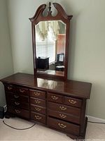 Full view of dresser showing twelve drawers with brass handles and attached mirror with carved wooden frame.