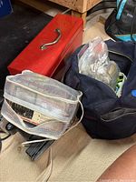 Photo of red metal toolbox, blue duffel bag with electrical supplies, and Micronta multitester in white mesh case