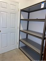 Full view of Whalen Z Beam Metal Shelf unit positioned against wall near a door, showing four wide shelves and sturdy black frame.
