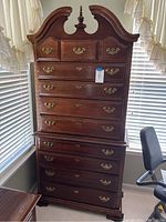 Full front view of midtone wood highboy dresser in room