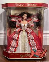 Full front view of Barbie doll in original box, showing red and white layered dress with gold lace trim and Happy Holidays branding.