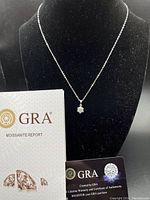 Full view of the necklace displayed on a black mannequin bust with the GRA certificate and authenticity card placed in front.