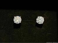 Front view of the pair of white Moissanite stud earrings in a black display.