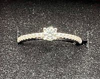 Close-up image of the silver ring showcasing the center moissanite stone and detailed band.