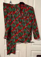 Front view of candy cane patterned blazer and matching pants hanging on wall