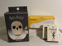 Photo showing sealed boxes of Harry Potter Hedwig touch light, duck-themed sleep lamp, and two Queeng playing card decks.