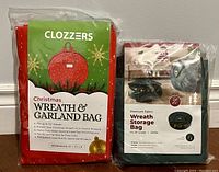Photo showing both wreath storage bags in packaging: Clozzers red Christmas Wreath & Garland Bag and Zober green Premium Fabric Wreath Storage Bag.