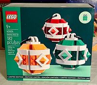 Front of boxed Lego Limited Edition Christmas Decor Set 40604 showing the three finished ornament designs in red, green, and orange.