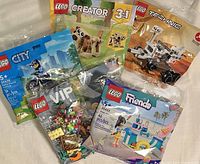 Photo showing five Lego poly bag sets: Lego City police motorcycle, Lego VIP small mini builds set, Lego Creator 3-in-1 dog figure, Lego Technic small vehicle, and Lego Friends skate ramp set.