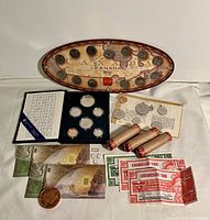 Photo showing three Royal Canadian Mint coin sets from 1968, 1985, and 1999 with coin rolls, some gold, silver and copper coins, and Canadian Tire Money bills.
