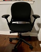Front view of black Steelcase office chair, showing cushioned seat, backrest, and adjustable armrests on five-wheel base.