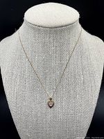 Full view of the pendant and chain displayed on a black and beige fabric bust