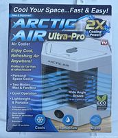 Front and side view of boxed Arctic Air Ultra-Pro personal air cooler, highlighting features such as 2x cooling power, eco-friendly design, and modes including mist and fan/mist.