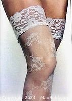 Close-up of sheer thigh-high pantyhose with lace floral top band and subtle floral pattern in legs.