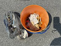 Overall lot photo showing orange bucket with various door hardware and electrical parts inside along with plastic bags containing more items.