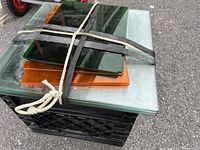 Stack of various glass shelves of different colors and sizes tied with ropes.