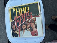 The Bee Gees Love Collection vinyl album cover on top of a plastic container.