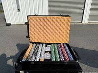 Poker chips in multiple colors and two decks of cards inside an open black carrying case.