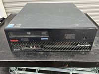 Front and top view of Lenovo ThinkCentre desktop computer indicating DVD drive and connectivity ports including USB and audio jacks.