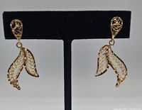 Pair of earrings displayed on a black stand showing front filigree design