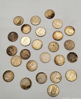 Photo showing 26 Canadian dimes arranged in a semi-regular pattern on a white background with various tarnish and wear marks visible.