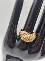 Ring displayed on black plastic stand showing overall domed carved surface