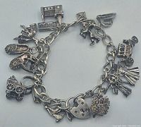 Front view of the entire sterling silver charm bracelet laid flat showing all 15 charms and padlock closure.