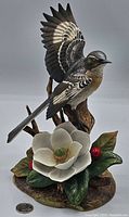 Full view of the Birks vintage figurine showing a mockingbird perched with wings open and a large magnolia flower with leaves and red berries at the base.