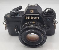 Front view showing Nikon EM camera with mounted 50mm f/1.8 lens, lens markings and serial number 1418535 visible.