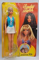 Front view of the Tuesday Taylor doll in original blister packaging with colorful cardboard backing featuring various hair colors.