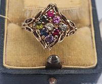 Ring in presentation box shot from top showing cluster of colored stones