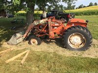 Side view of tractor showing front end loader attachment, loader arms, and bucket with chipped paint and surface rust