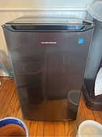 Front view of the black Hamilton Beach bar fridge showing the brand logo and door design.