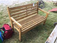 Front-side angle of wooden bench showing slatted seat, backrest, curved armrests, and visible finish wear.