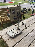 Shopcraft bench top drill press showing vertical mounting post, adjustable base, and motor housing with operating handles.