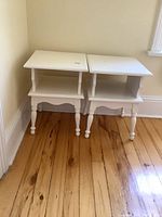 Pair of matching painted wood end tables displayed side by side on wooden floor, showing overall shape and size.