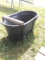 Angled exterior view of black Rubbermaid trough on grass with wood plank overlay