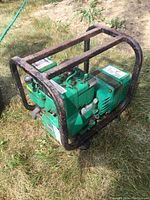 Full side view of the green Coleman Powermate generator with rusted metal frame on grass.