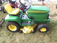 Side view showing green hood, yellow mower deck, tires and seat tear