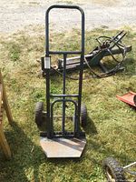 Front view of metal hand truck showing vertical frame, handle, and loading platform with wear and rust