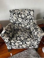 Front view of upholstered recliner chair showing overall shape, fabric pattern, and wood legs