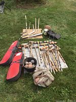 Photo showing full layout of croquet mallets, balls, hockey sticks, baseball bat, soccer ball, bike rack, and two sports bags on grass.