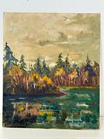 Front view of the signed oil on board painting showing a lake with colorful trees reflecting in the water under a cloudy sky.