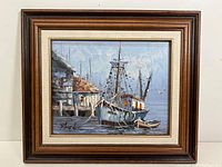 Framed oil painting showing the entire harbor scene with fishing boat and dock buildings, signed by the artist.