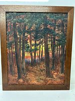 Full view of watercolour painting in wooden frame depicting forest with detailed trees and ferns at sunset.