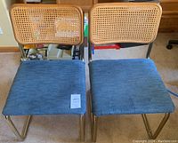 Two bent frame chairs side by side, showing blue seat fabric, brass-tone tubular frames, and rattan wood backs.