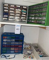 Three large organizer drawers in gray, green and blue filled with beads sorted by color and type.